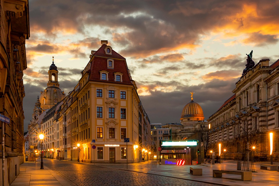 Buildings in Dresden, Germany are softly lit against a setting sun and partially cloudy sky.